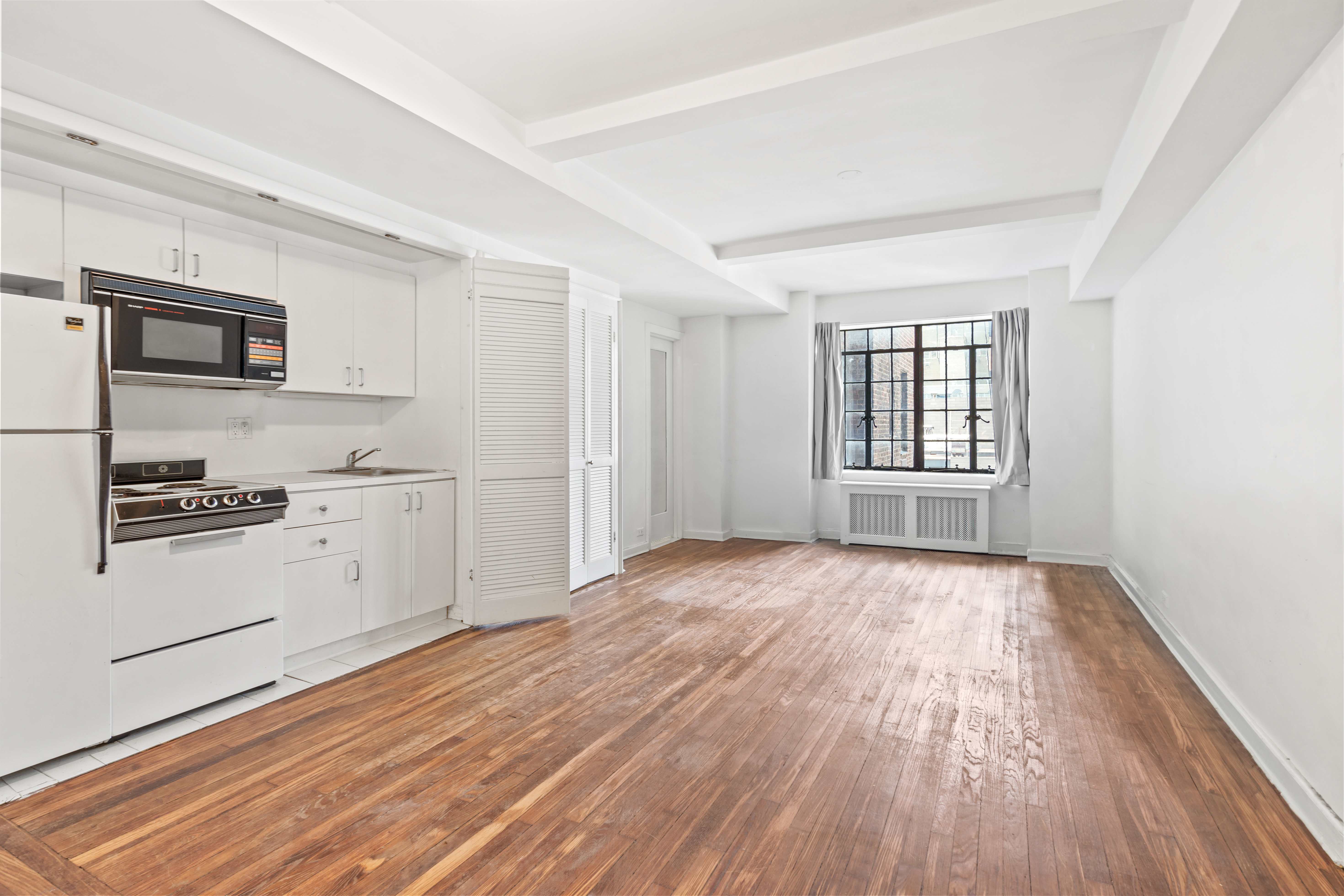 45 Tudor City Place, Unit 1708 Manhattan, NY 10017 - Photo 2 of 14 a view of a kitchen with wooden floor and electronic appliances