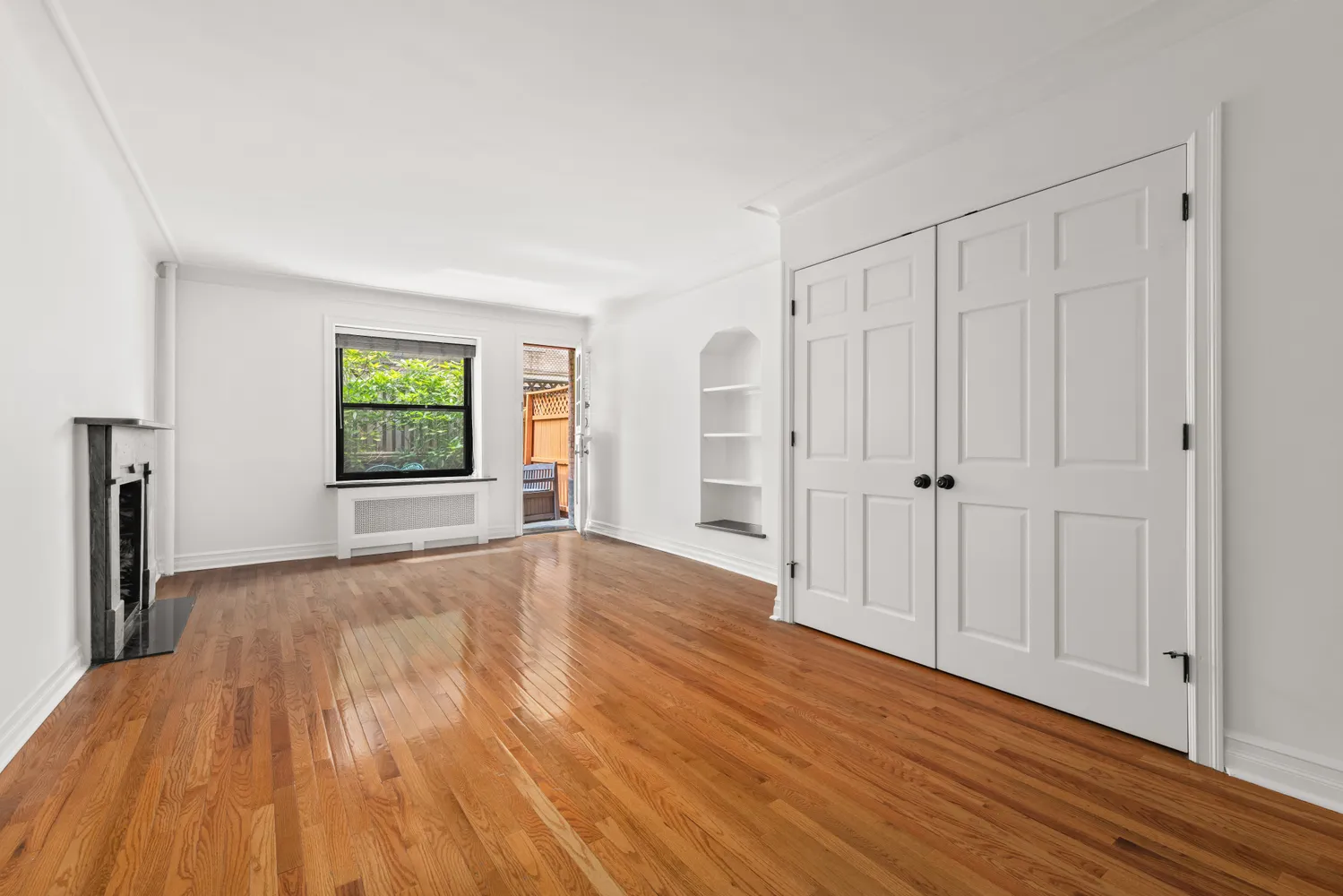 a view of an empty room with window and wooden floor