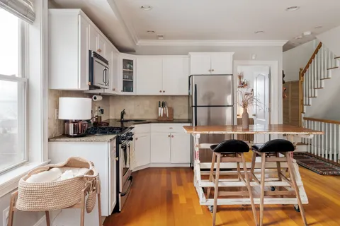 a kitchen with stainless steel appliances kitchen island granite countertop a table chairs and a refrigerator