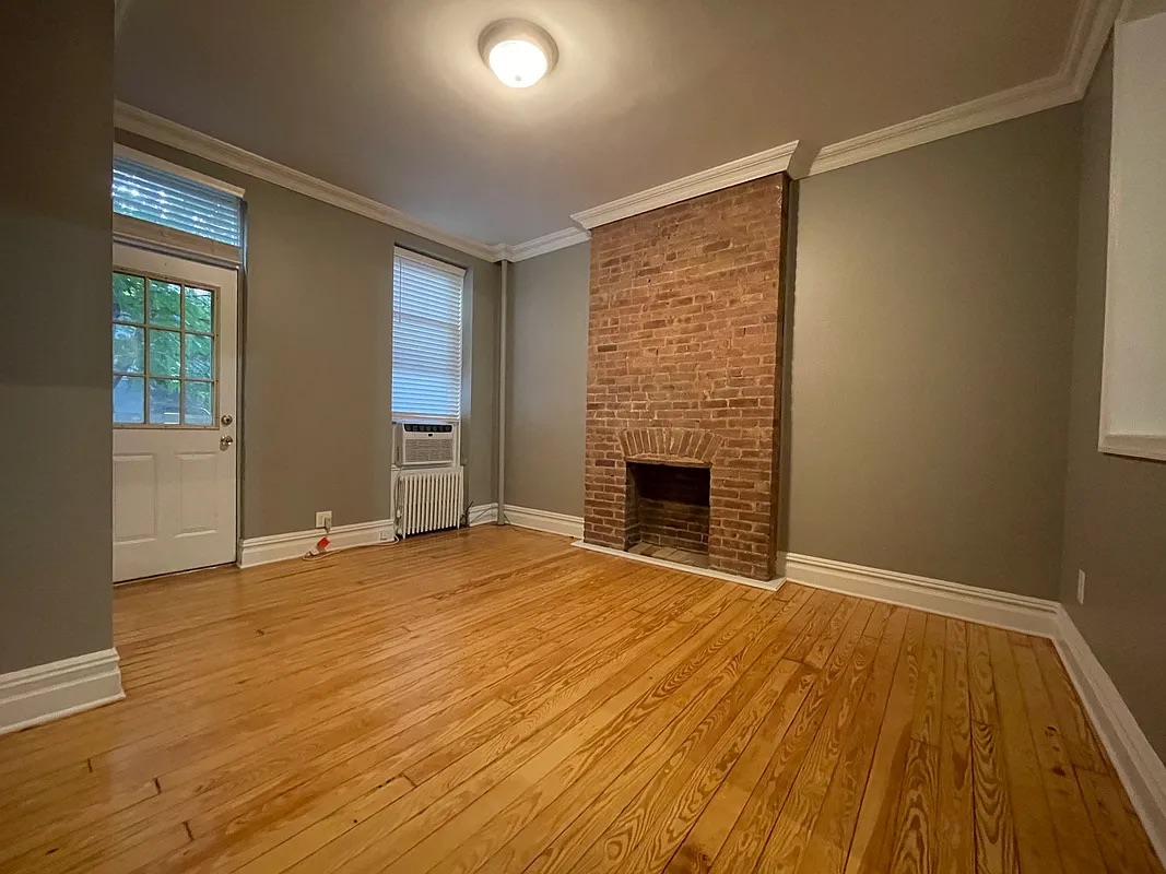 a view of empty room with wooden floor and fireplace
