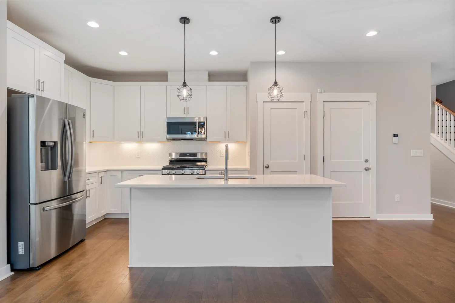 a kitchen with stainless steel appliances granite countertop a refrigerator a sink dishwasher a stove and white cabinets with wooden floor