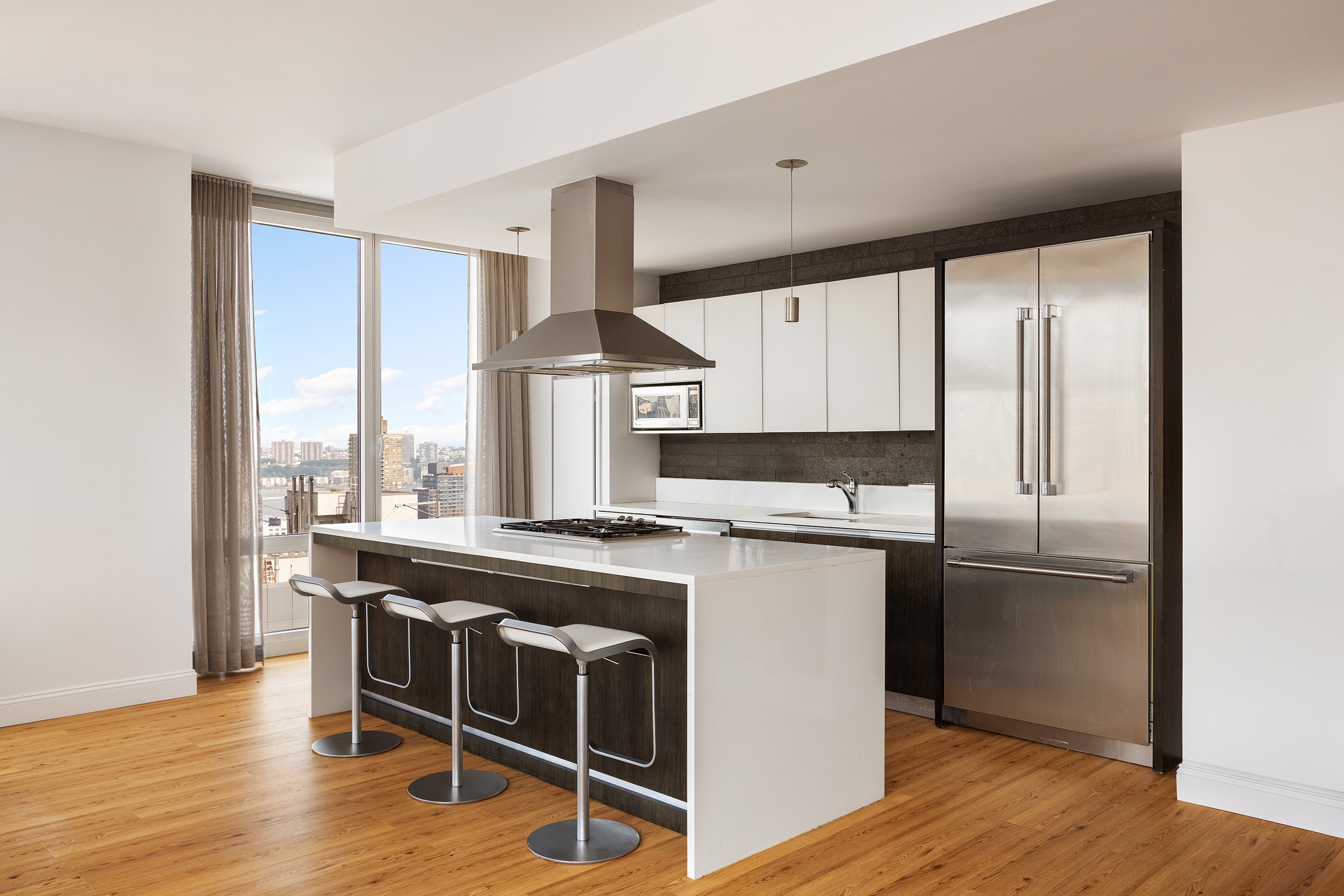 247 West 46th Street, Unit 3103 Manhattan, NY 10036 - Photo 3 of 14 a kitchen with kitchen island granite countertop a stove a refrigerator and wooden floor