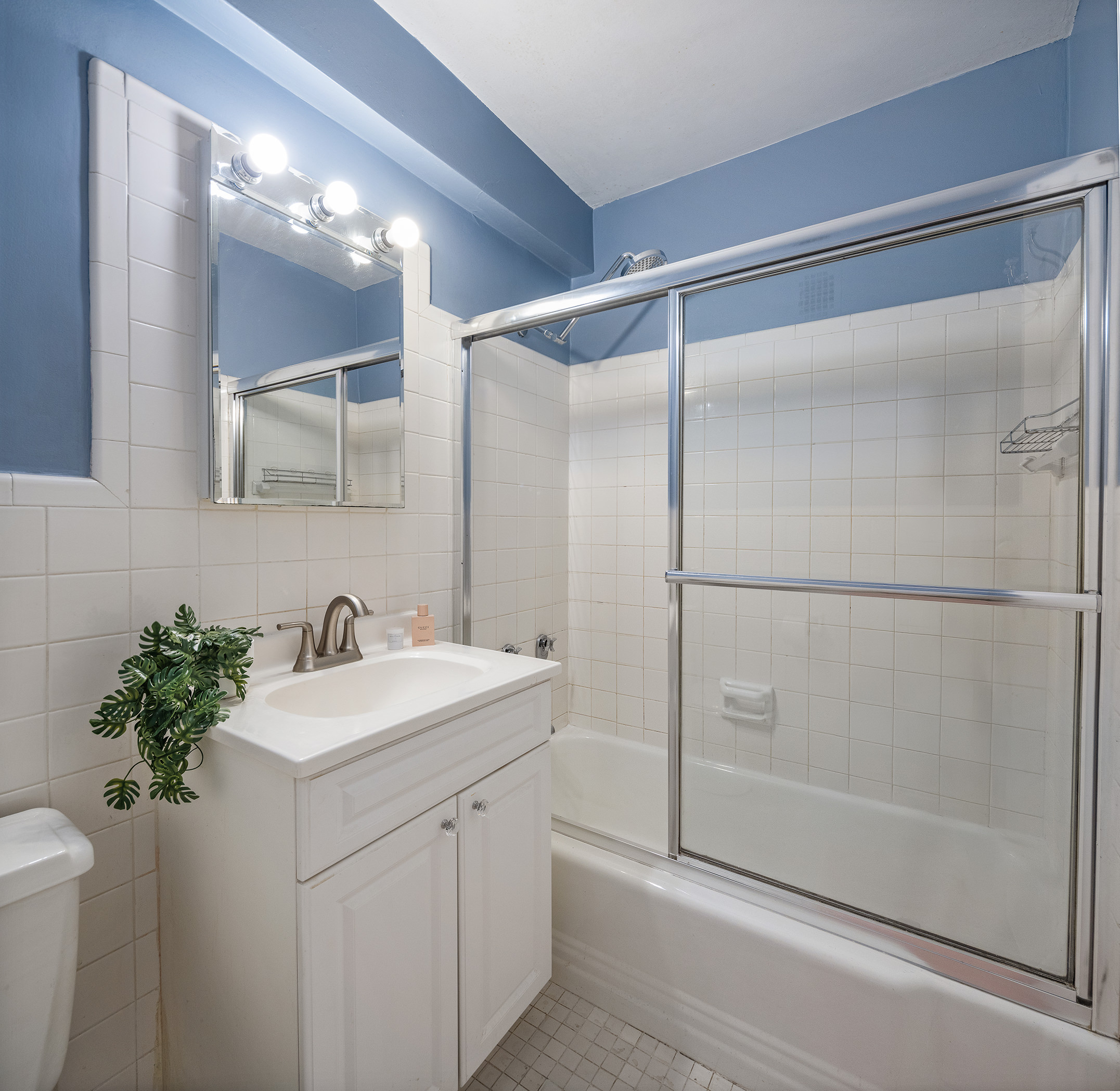 235 East 87th Street, Unit 5G Manhattan, NY 10128 - Photo 8 of 13 a bathroom with a shower sink vanity and mirror