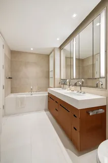 a spacious bathroom with a double vanity sink large mirror and a bathtub