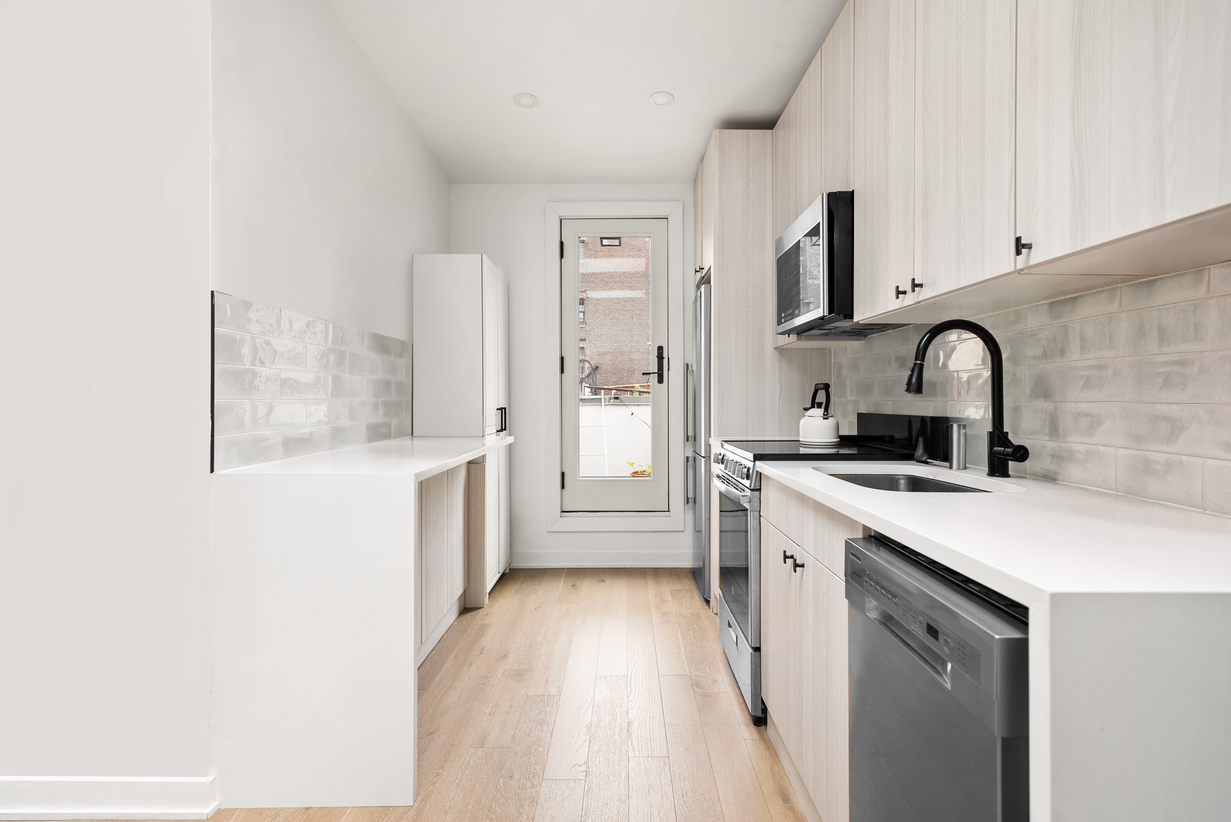 275 Bleecker Street, Unit 4 Manhattan, NY 10014 - Photo 3 of 10 a kitchen with stainless steel appliances a sink a stove top oven a counter space and cabinets