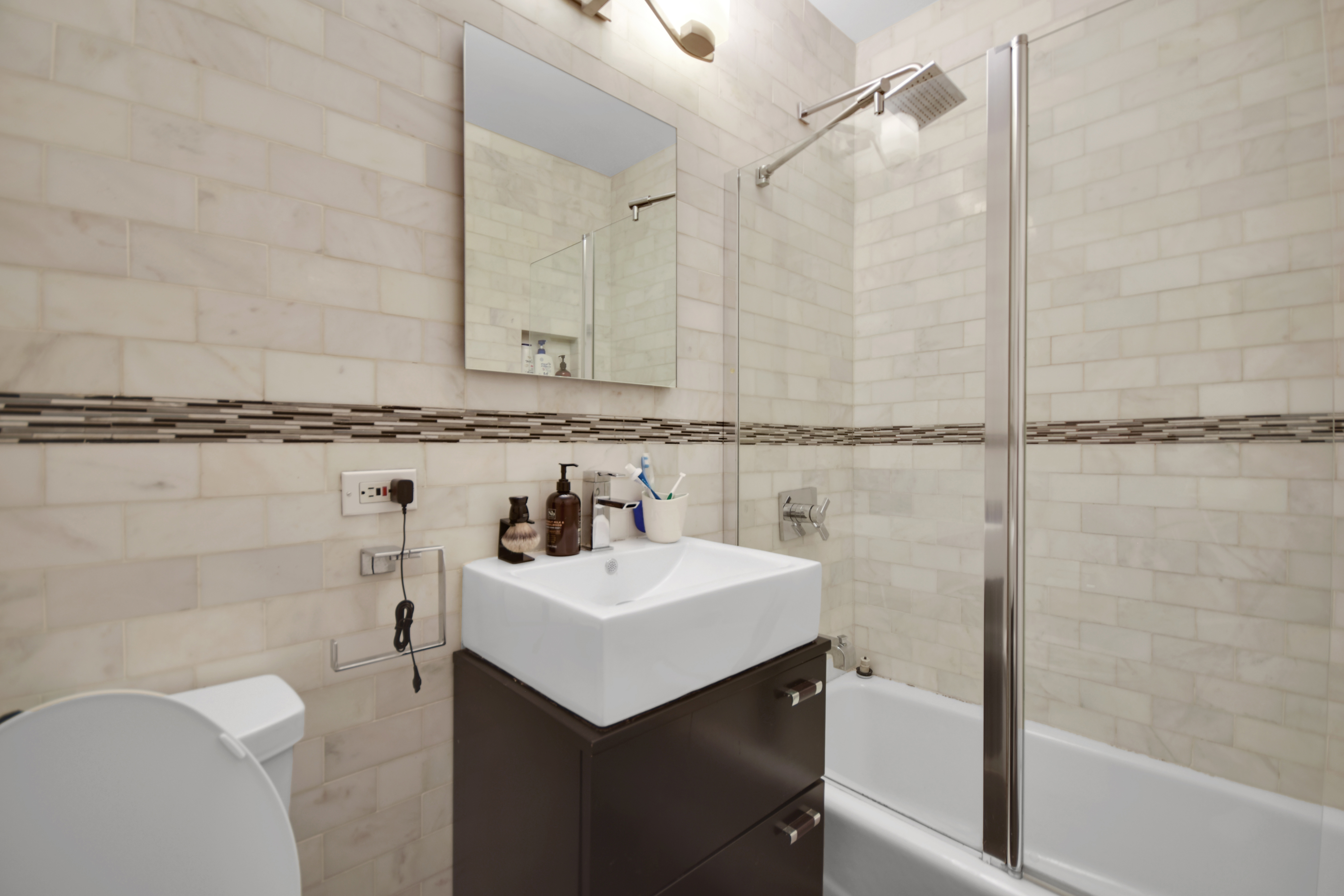 4-74 48th Avenue, Unit 34G Queens, NY 11109 - Photo 8 of 9 a bathroom with a sink a toilet and shower