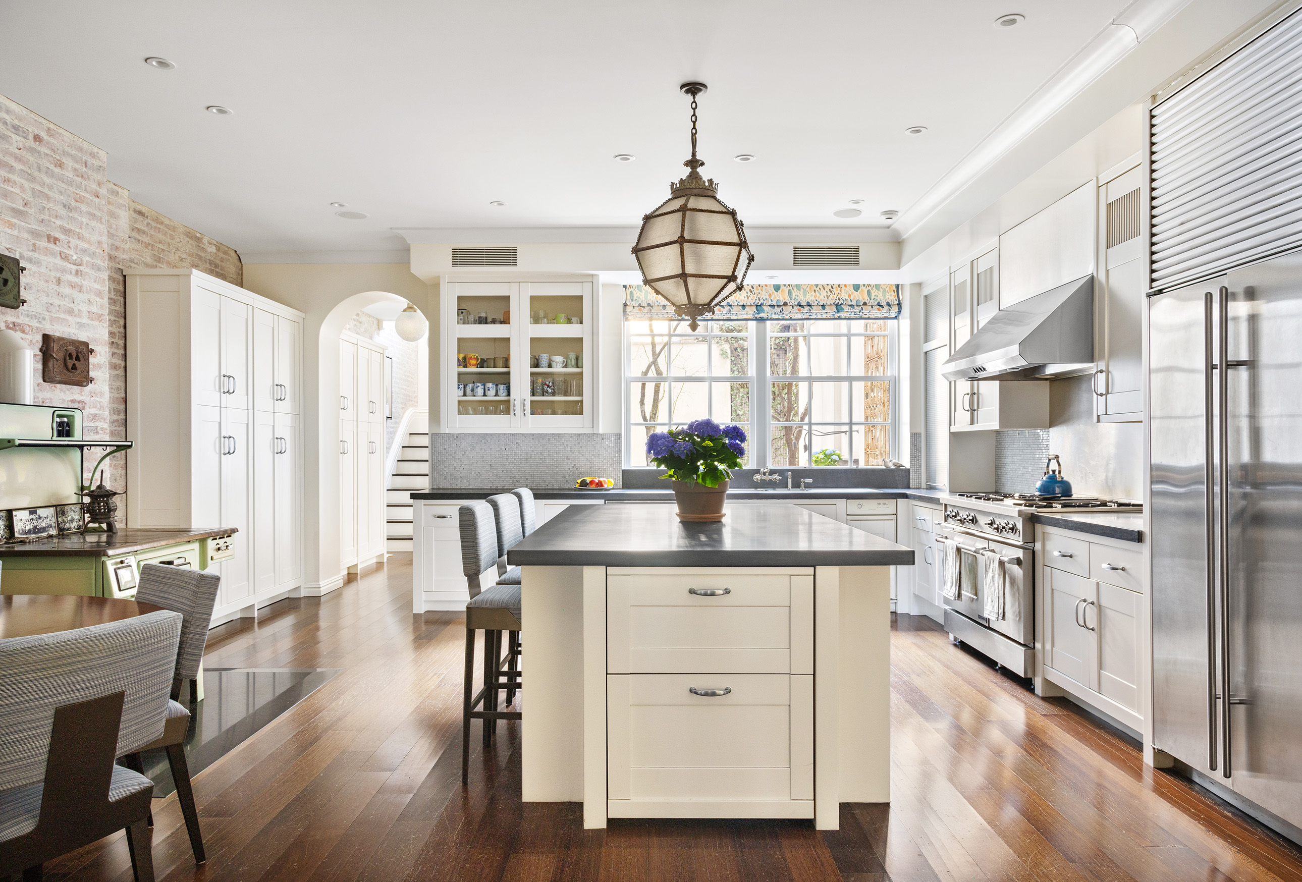 127 East 73rd Street Manhattan, NY 10021 - Photo 21 of 40 a kitchen with stainless steel appliances a dining table chairs stove and refrigerator