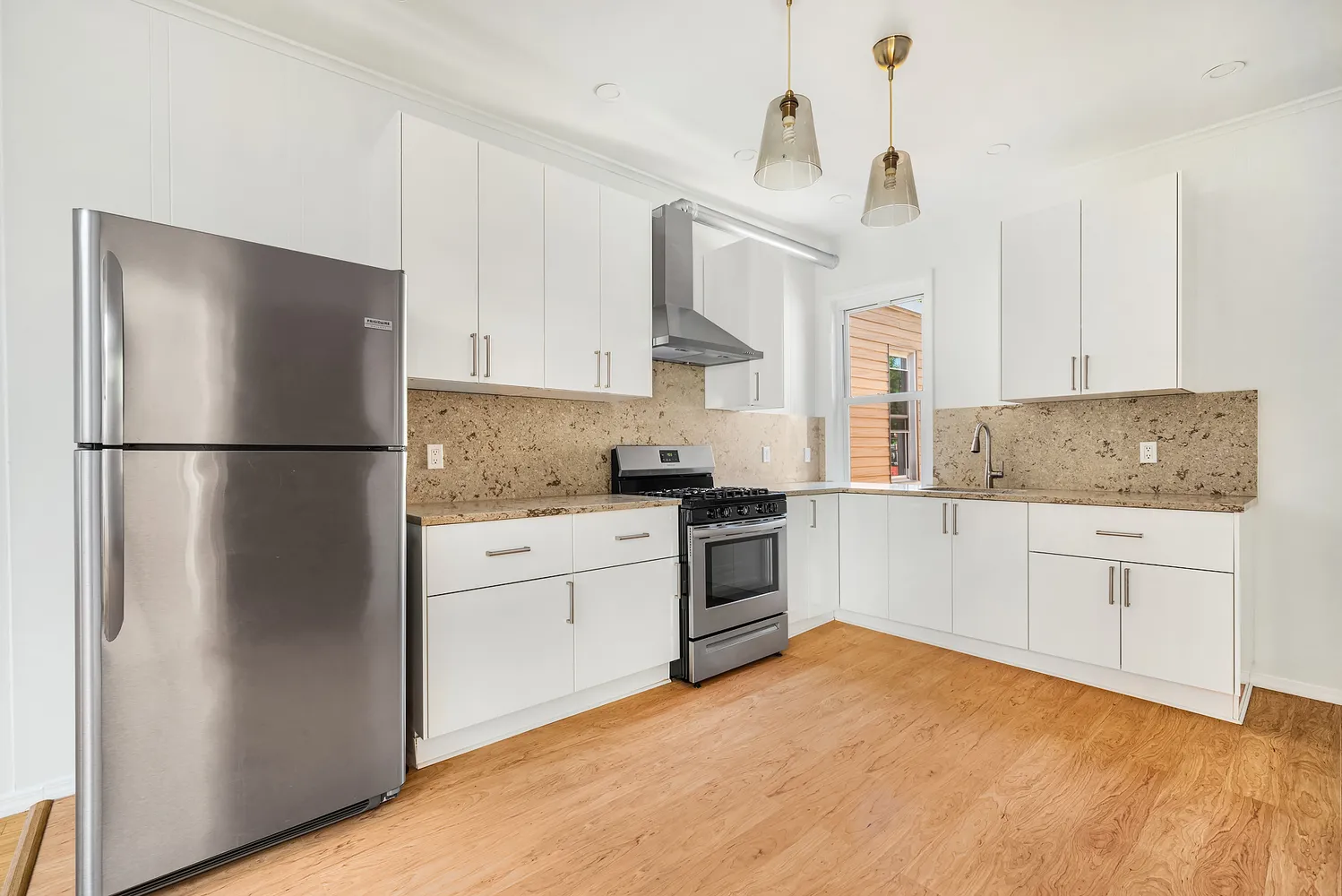 a kitchen with granite countertop a refrigerator stove and white cabinets
