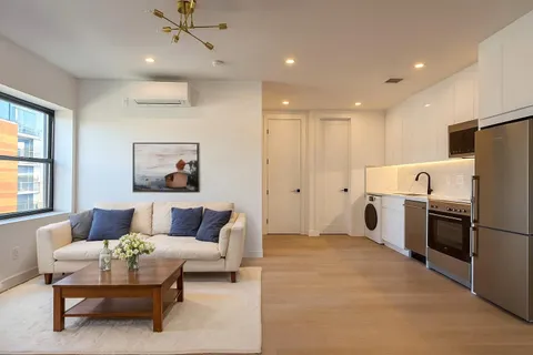 a living room with furniture and a refrigerator