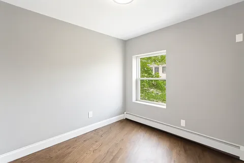 an empty room with wooden floor and window