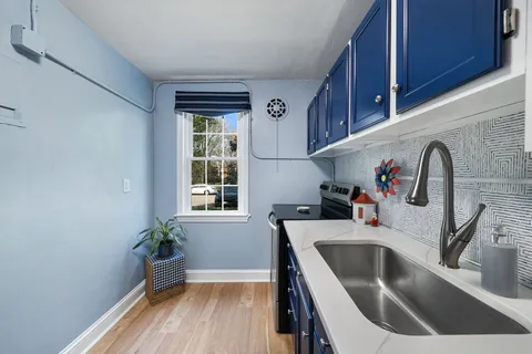 a kitchen with a refrigerator a sink a faucet cabinets and a window