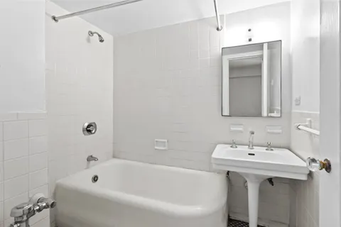a bathroom with a tub sink and mirror