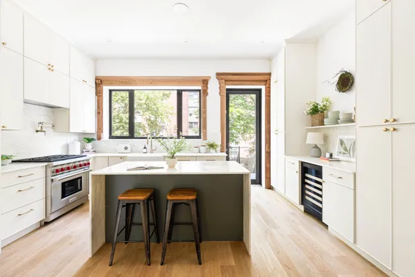a kitchen with kitchen island a stove a sink a dining table and chairs