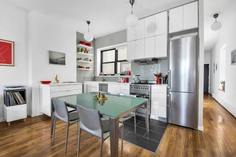 a kitchen with stainless steel appliances granite countertop a dining table chairs refrigerator and sink
