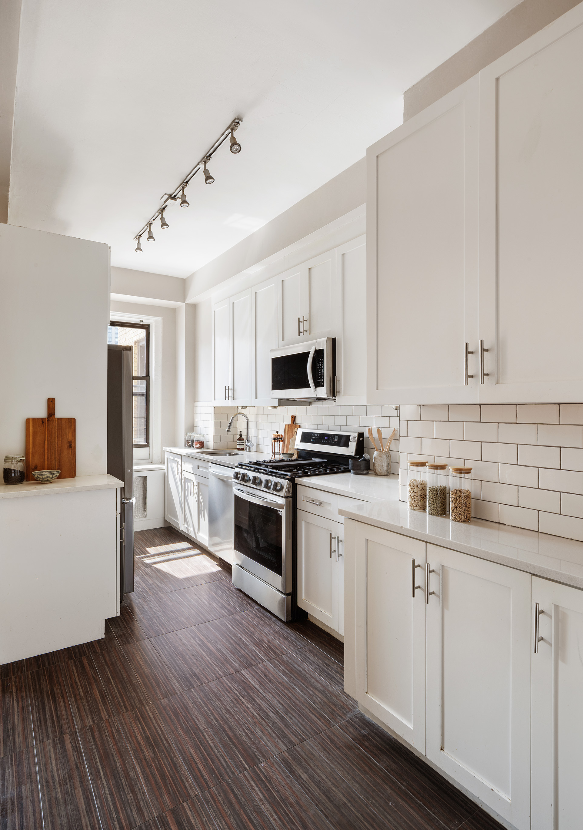 215 West 92nd Street, Unit 10F Manhattan, NY 10025 - Photo 4 of 11 a kitchen with stainless steel appliances white cabinets a sink a stove a microwave and wooden floors