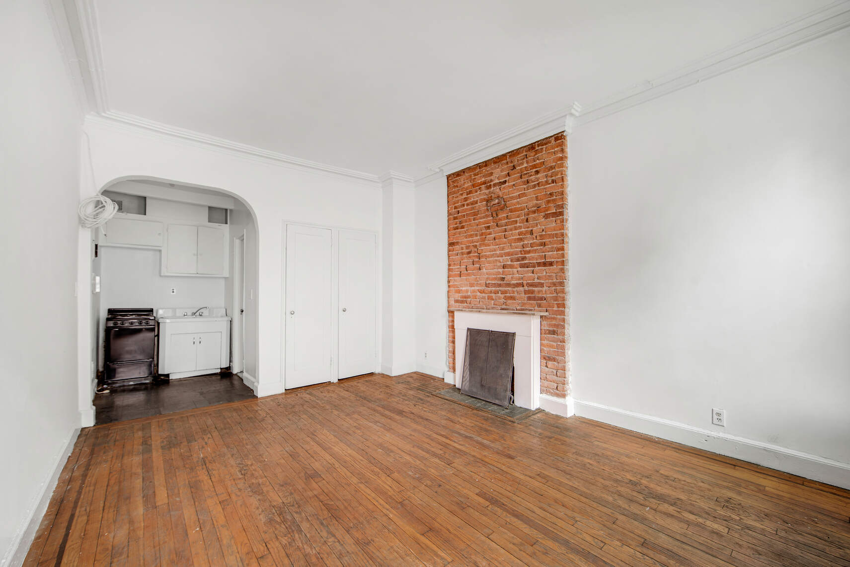 337 East 18th Street Manhattan, NY 10003 - Photo 12 of 16 a view of empty room with wooden floor and fireplace