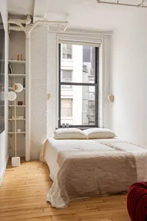 a large white bed in a bedroom next to a window