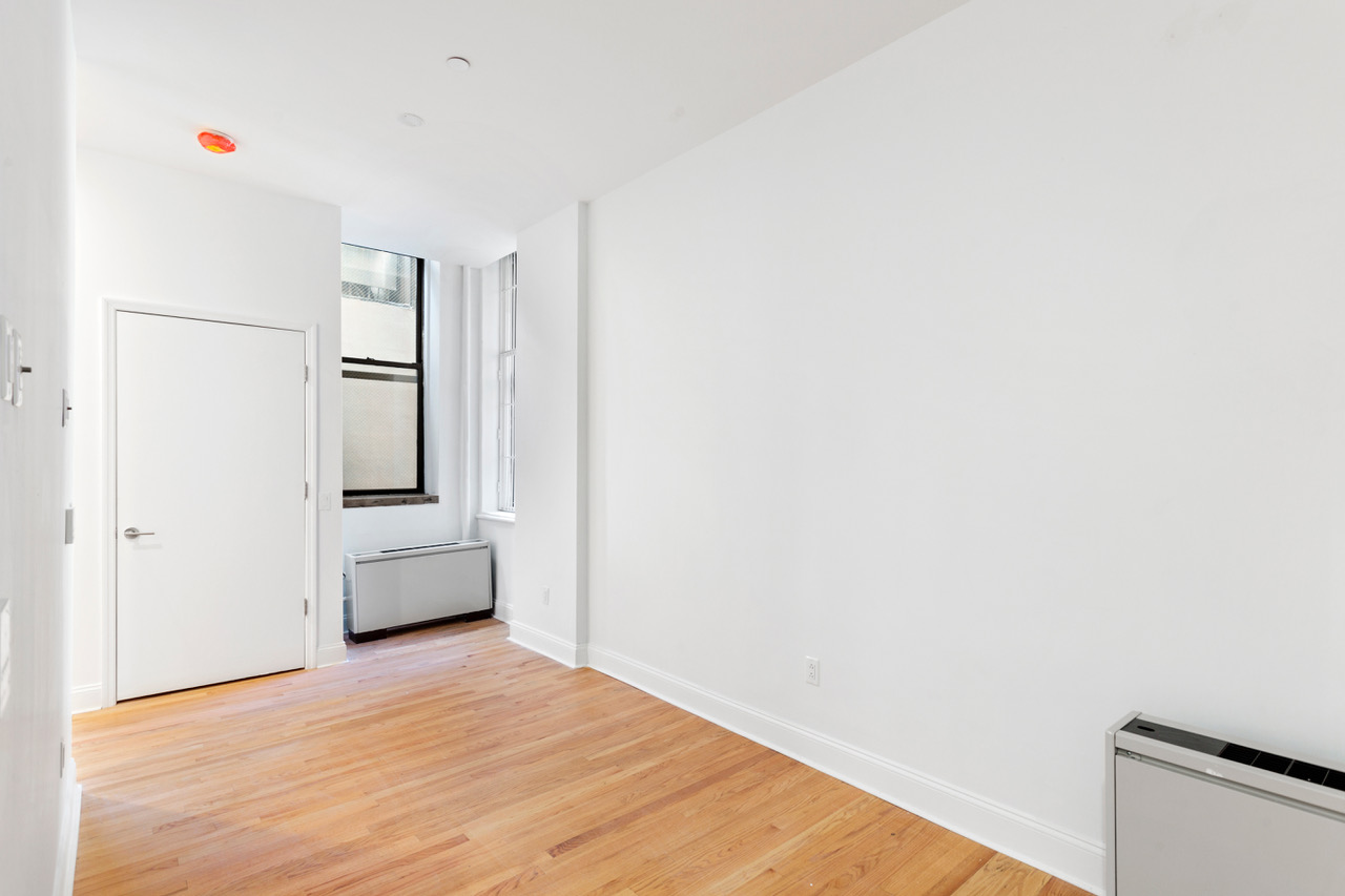 281 Grand Street, Unit 2R Manhattan, NY 10002 - Photo 3 of 11 a view of a room with wooden floor and white walls