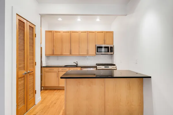 a kitchen with stainless steel appliances granite countertop white cabinets and a refrigerator