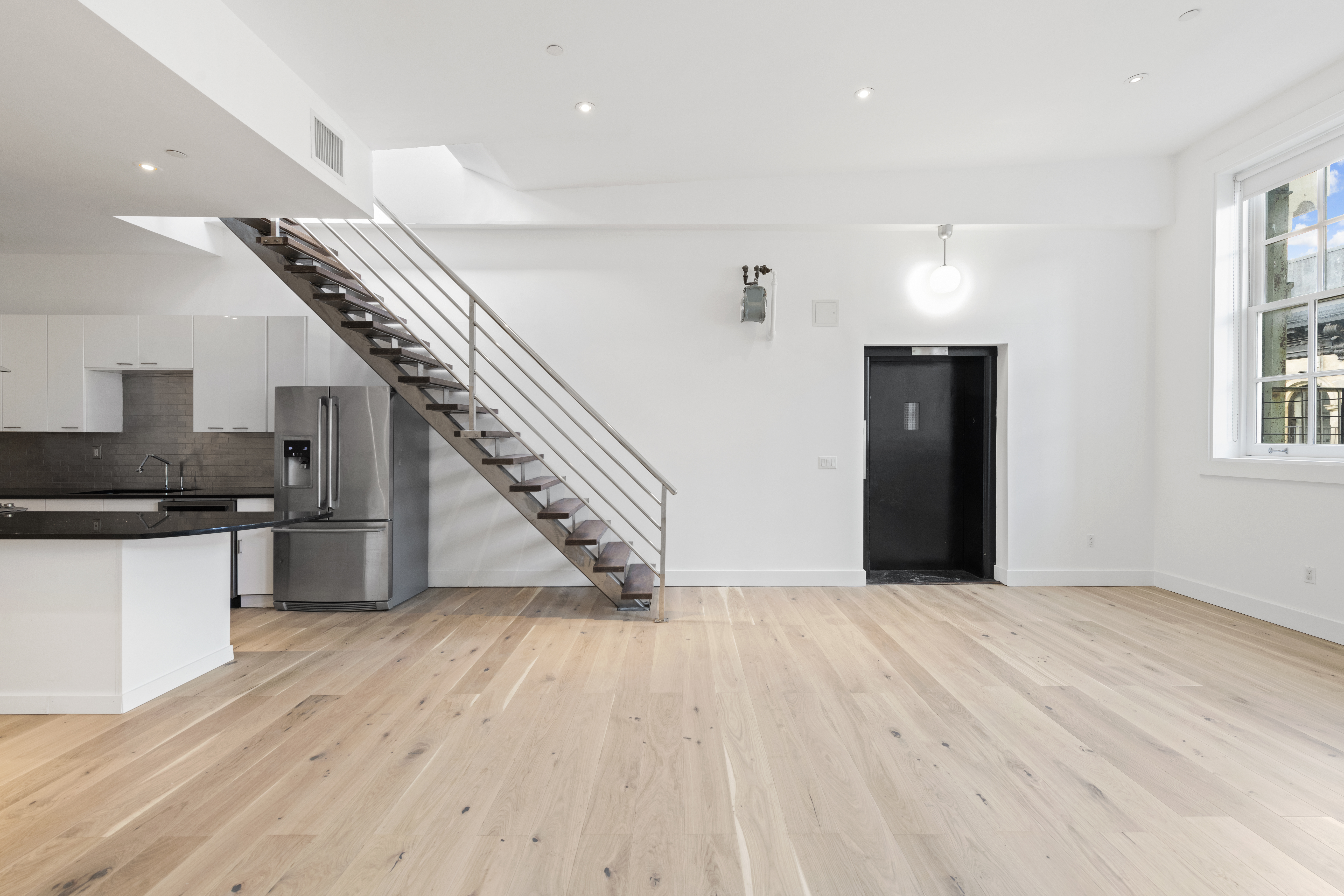 49 Walker Street, Unit PH Manhattan, NY 10013 - Photo 6 of 14 an empty room with wooden floor and staircase