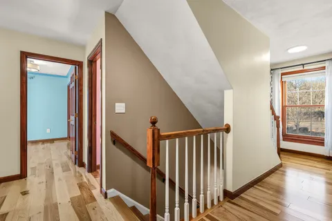 a view of a hallway with wooden floor and windows