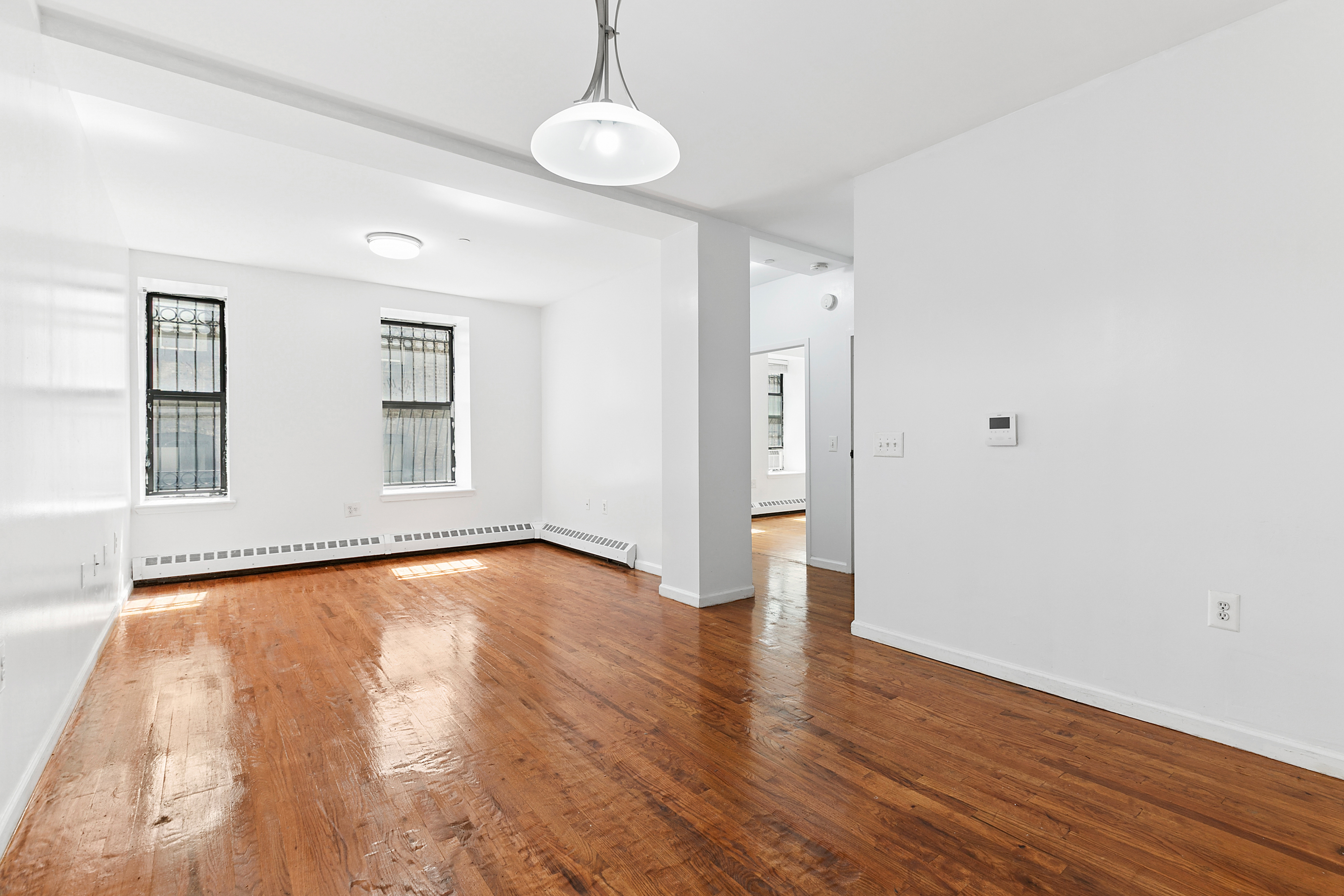 418 West 129th Street, Unit 4 Manhattan, NY 10027 - Photo 2 of 15 a view of an empty room with wooden floor and a window