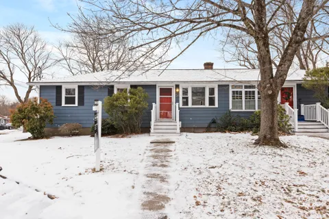 a front view of a house with a yard covered in snow