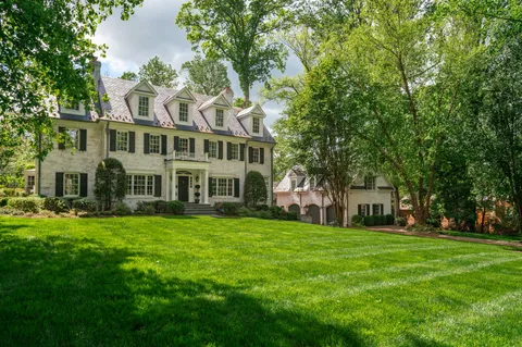 a view of a house with a big yard and large trees