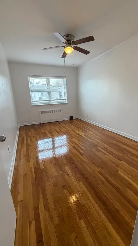 an empty room with wooden floor fan and windows