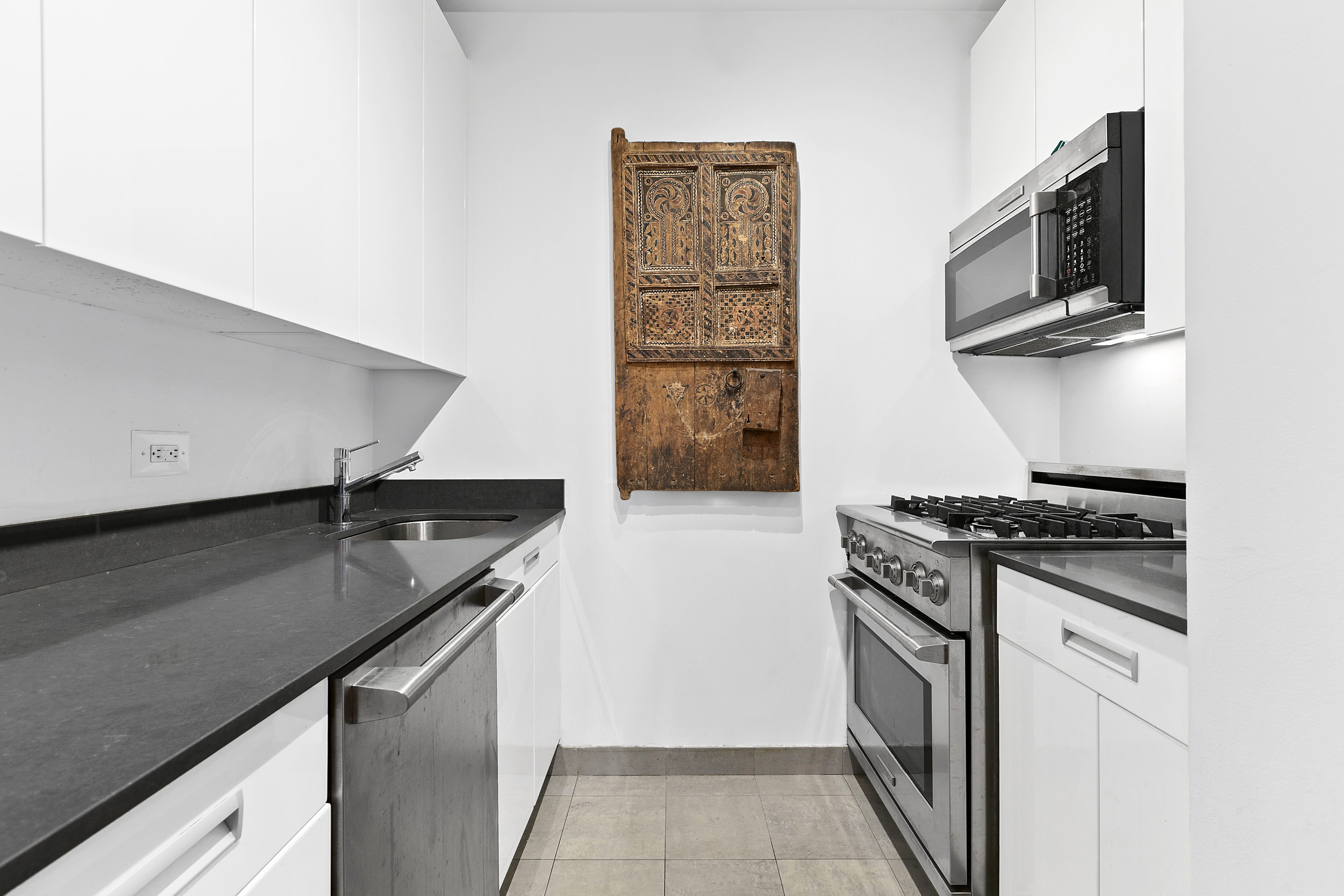 99 John Street, Unit 1101 Manhattan, NY 10038 - Photo 4 of 16 a kitchen with granite countertop a sink stove and microwave