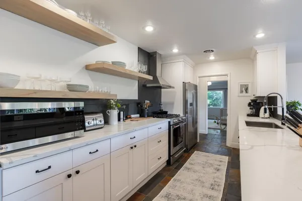 a large white kitchen with stainless steel appliances and a counter space