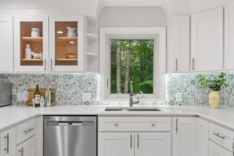 a kitchen with stainless steel appliances white cabinets and a large window
