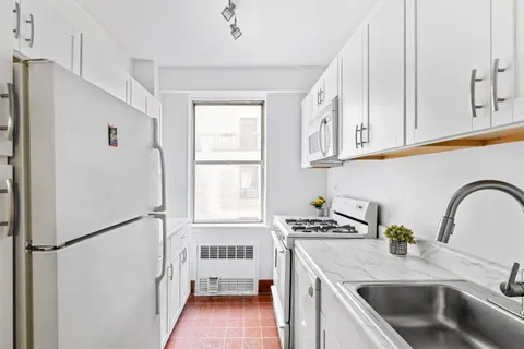 a kitchen with stainless steel appliances granite countertop a sink a refrigerator a window and white cabinets