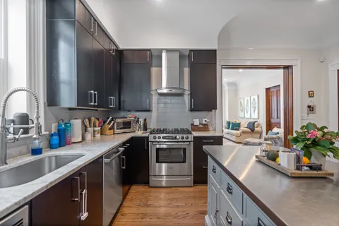 a kitchen with kitchen island granite countertop a sink stove and cabinets