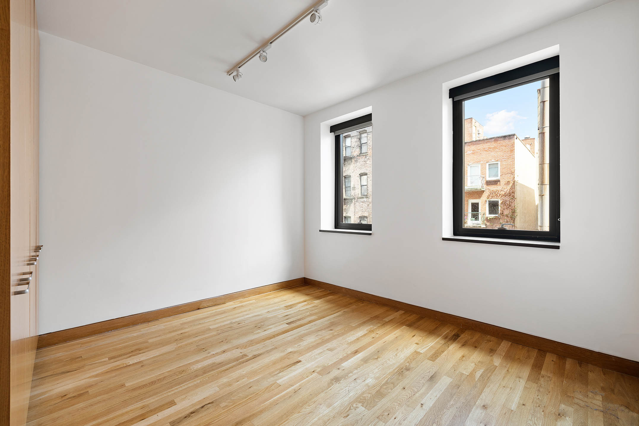 75 Sullivan Street, Unit 5S Manhattan, NY 10012 - Photo 10 of 12 a view of an empty room with wooden floor and a window