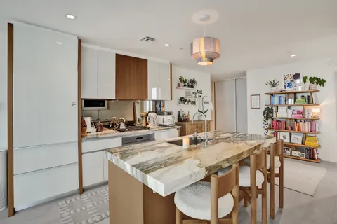 a kitchen with stainless steel appliances granite countertop a dining table chairs and a refrigerator