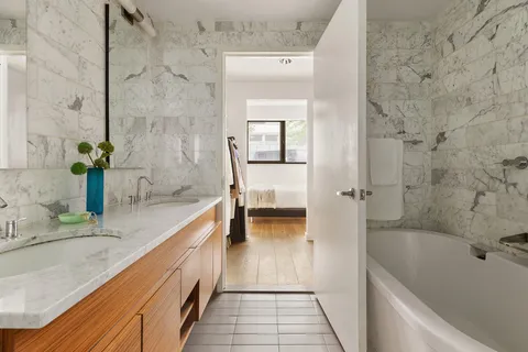 a bathroom with a granite countertop tub a sink and a large mirror