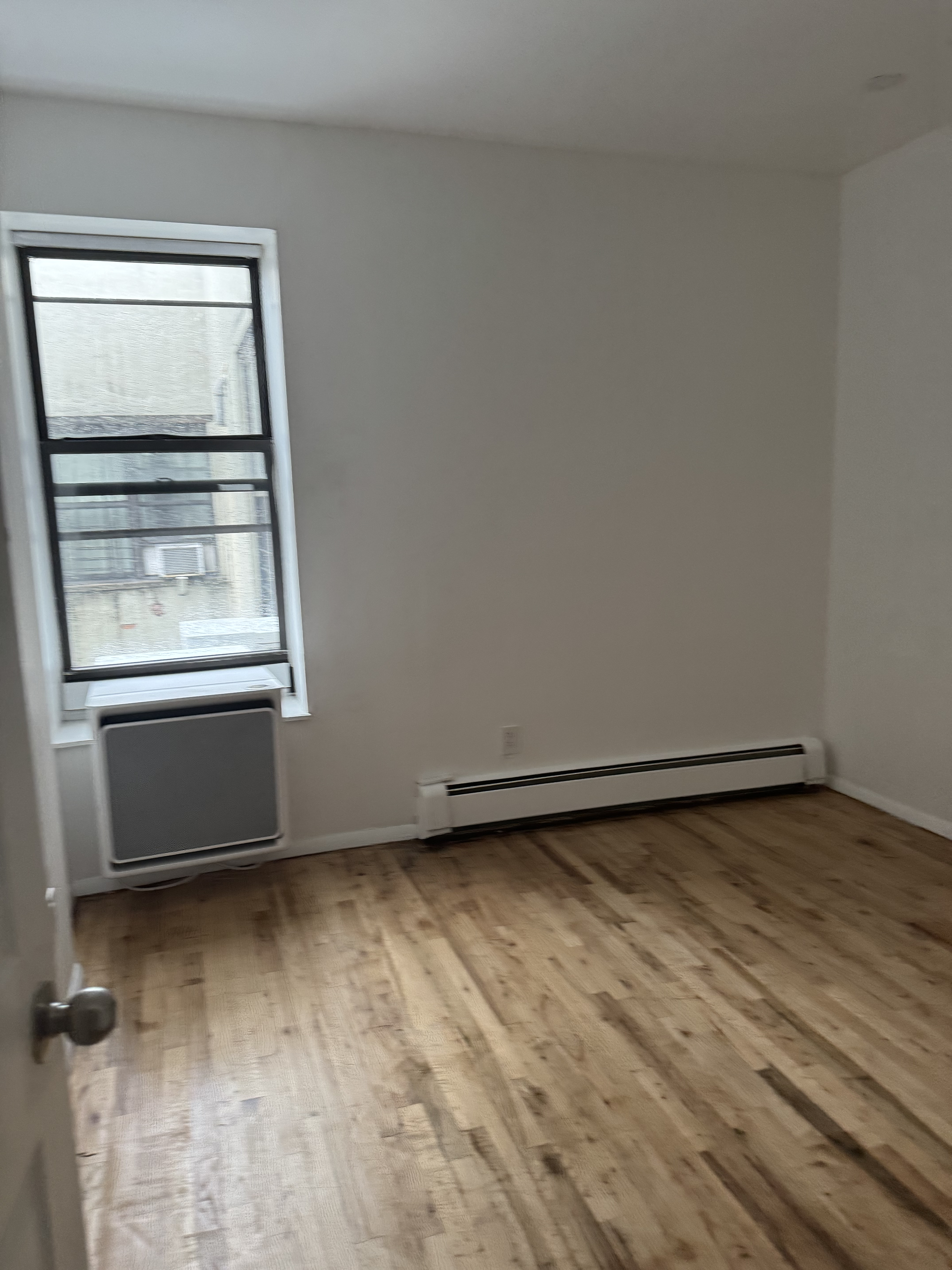 149 Sterling Street, Unit 4D Brooklyn, NY 11225 - Photo 4 of 7 an empty room with wooden floor and windows
