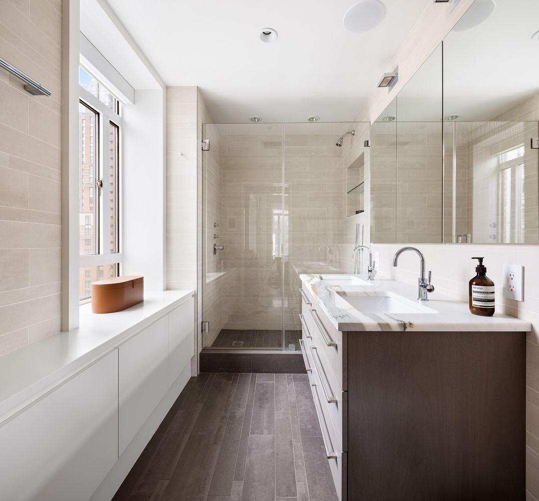 25 Central Park West, Unit 27J Manhattan, NY 10023 - Photo 11 of 13 a bathroom with a double vanity sink and mirror with shower