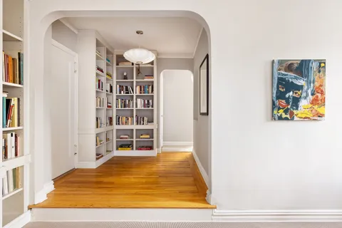 a view of a bedroom with wooden floor and shelf