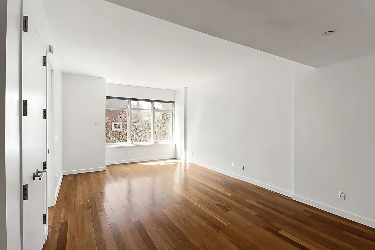 181 Clermont Avenue, Unit 101 Brooklyn, NY 11205 - Photo 3 of 9 a view of an empty room with wooden floor and a window