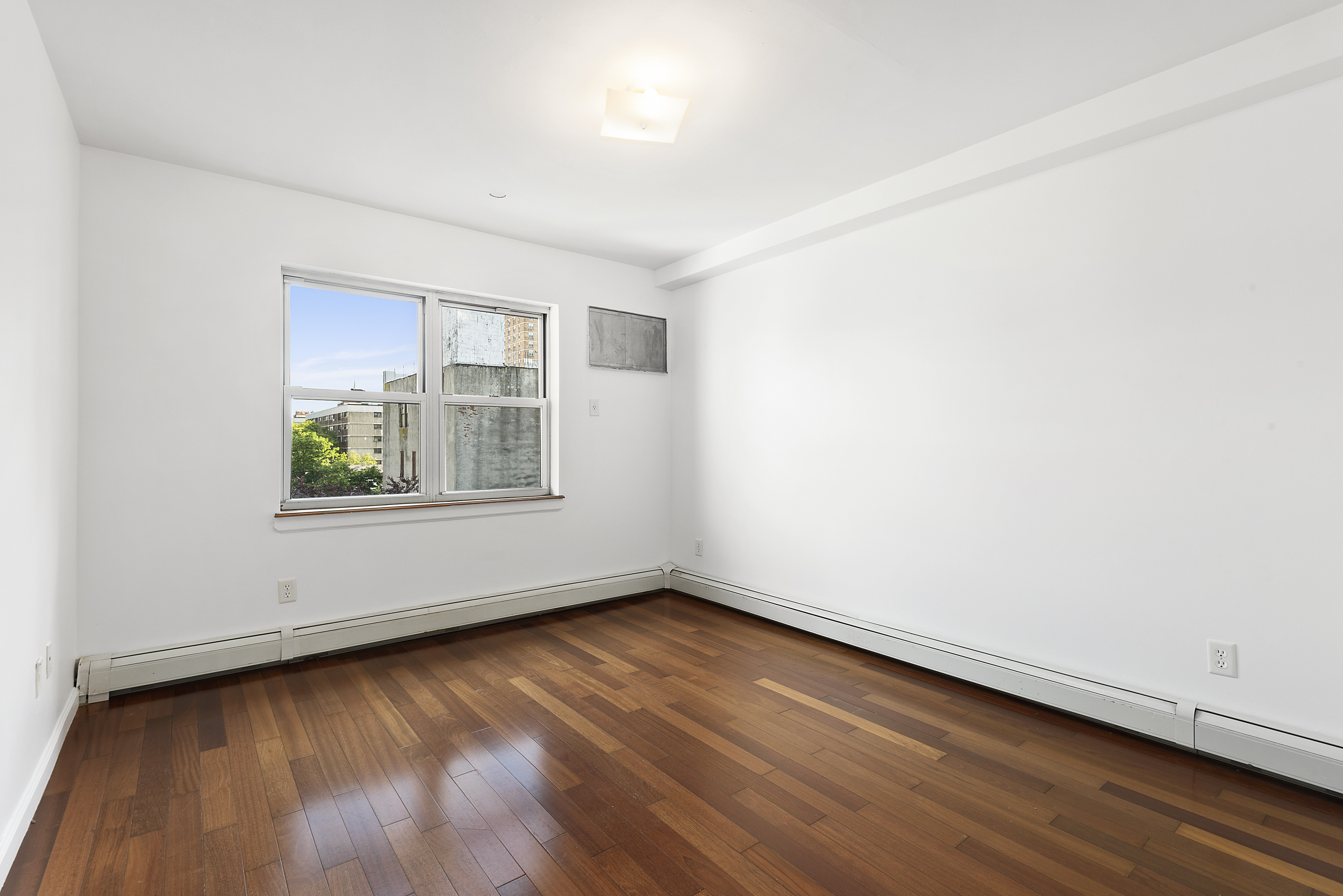 122 Boerum Street, Unit 4R Brooklyn, NY 11206 - Photo 6 of 9 an empty room with wooden floor and windows