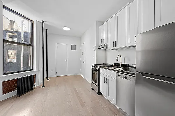 117 Mulberry Street, Unit 9 Manhattan, NY 10013 - Photo 2 of 5 a kitchen with stainless steel appliances granite countertop a stove a refrigerator and a refrigerator with wooden cabinets