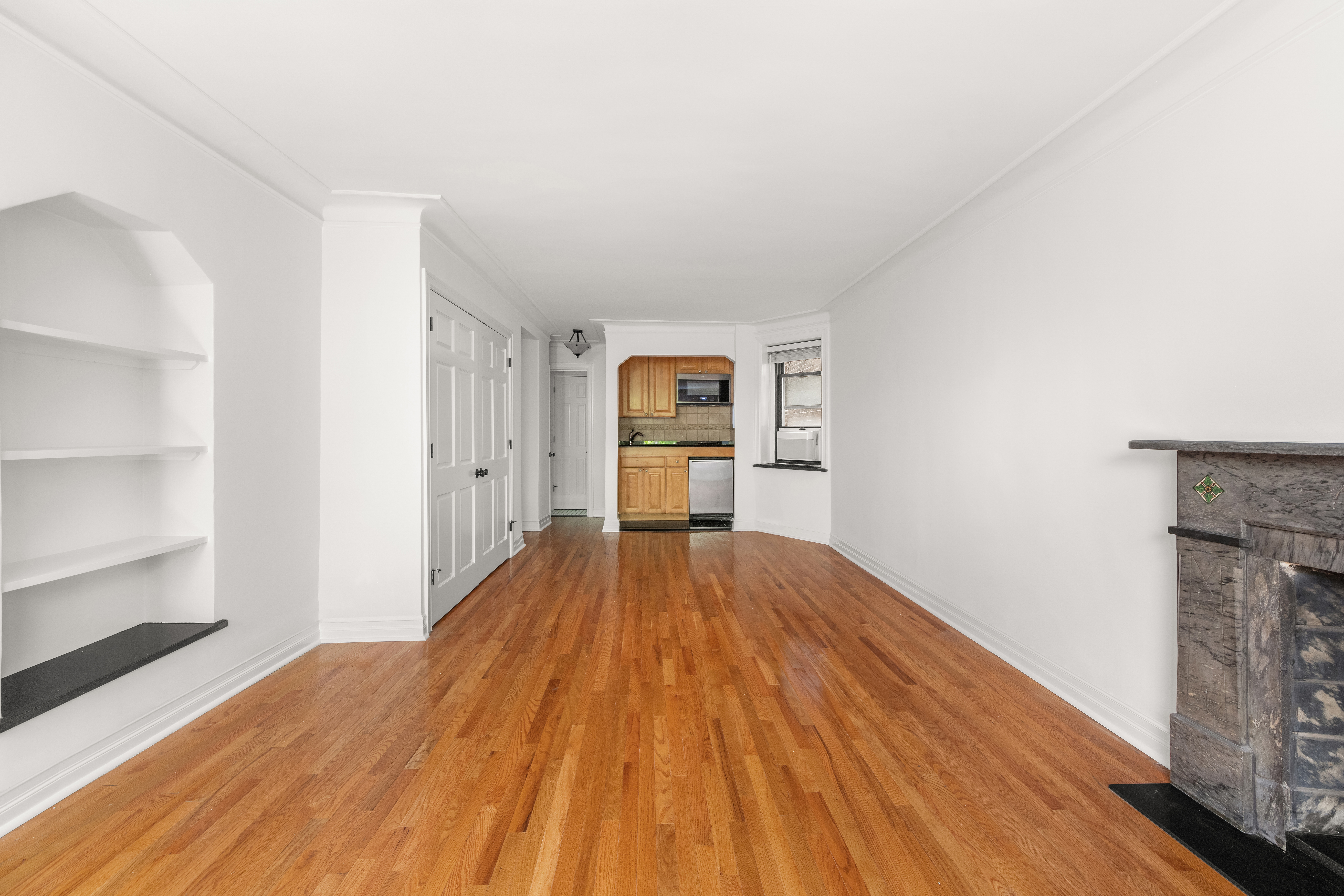 436 East 58th Street, Unit 1C Manhattan, NY 10022 - Photo 5 of 14 a view of empty room with wooden floor and fireplace