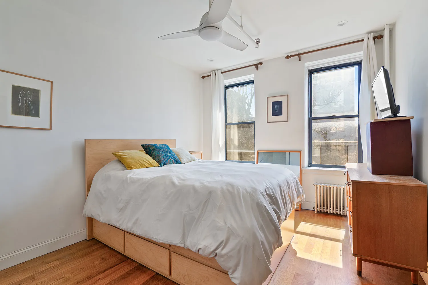 a bedroom with a bed and a flat tv screen on dresser