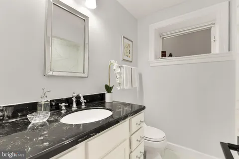 a bathroom with a granite countertop sink and a toilet