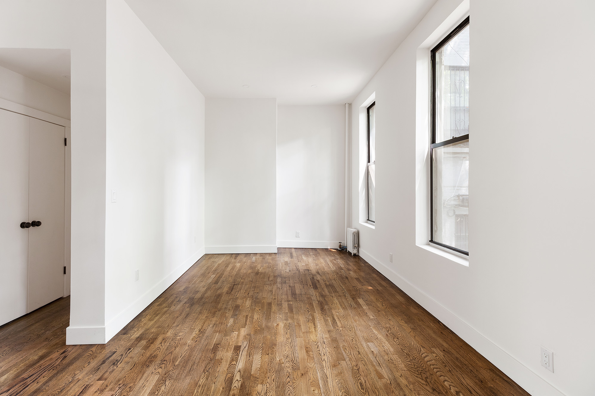 306 Gates Avenue, Unit 1A Brooklyn, NY 11216 - Photo 3 of 14 a view of an empty room with wooden floor and a window