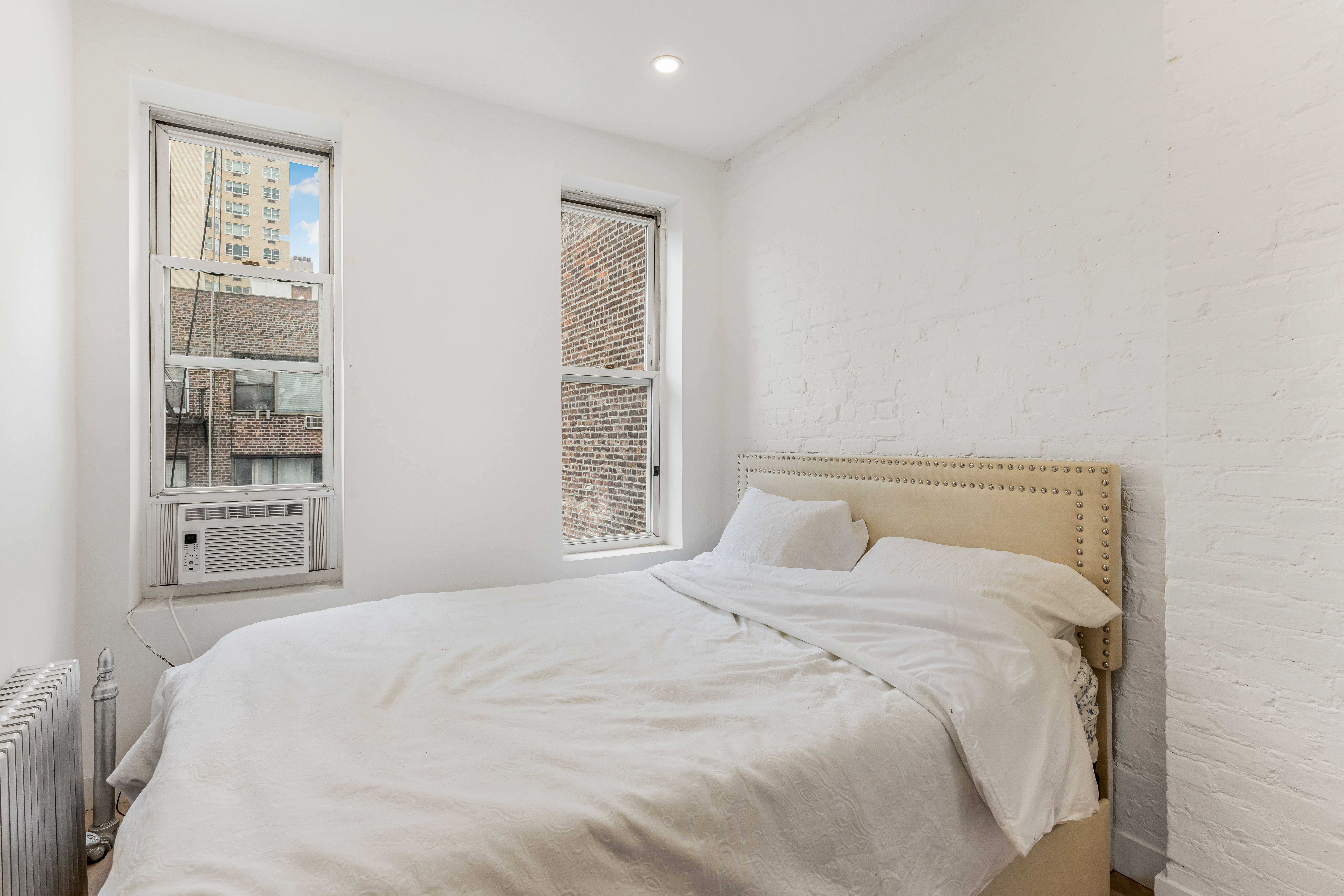 501 1/2 East 83rd Street, Unit 5E Manhattan, NY 10028 - Photo 6 of 7 a large bed sitting in a bedroom next to a window