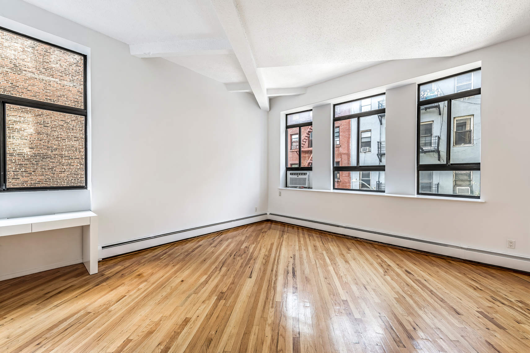 2 Cornelia Street, Unit 306 Manhattan, NY 10014 - Photo 2 of 13 a view of an empty room with wooden floor and a window
