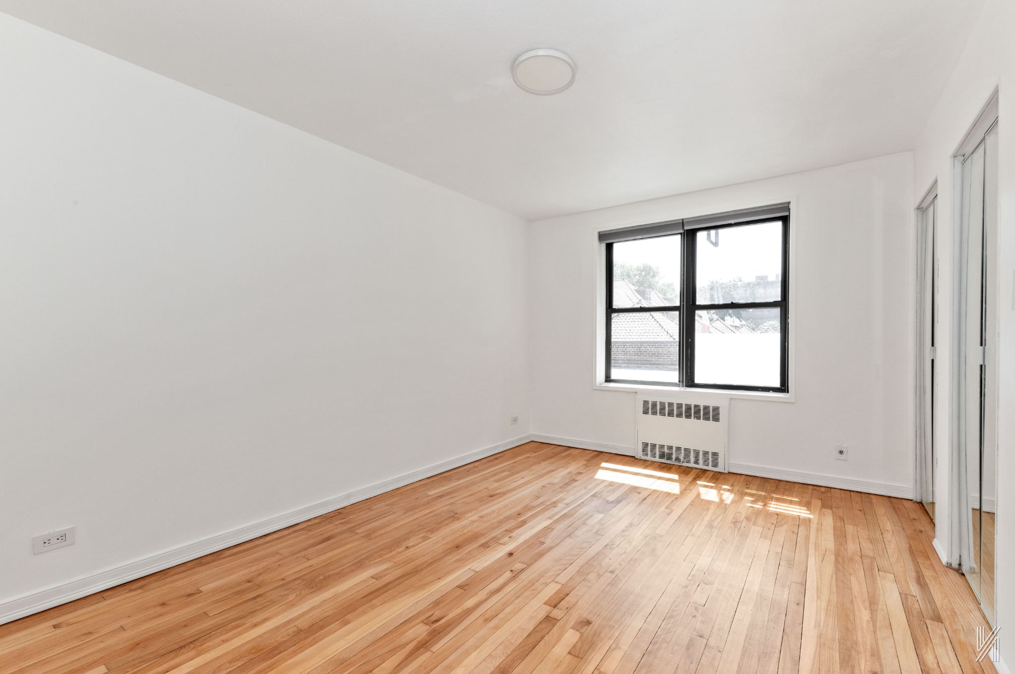 87-10 34th Avenue, Unit 1F Queens, NY 11372 - Photo 10 of 16 an empty room with wooden floor and windows